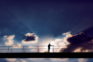 Photo of a man on a bridge with clouds in sky above